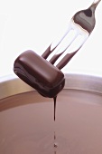 Piece of chocolate on fork, dipped in chocolate sauce