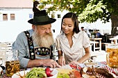 Asiatische Frau und Mann in bayerischer Tracht im Biergarten