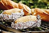 Baked potatoes and baguette on barbecue rack