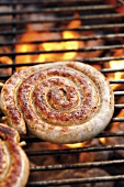 Coiled sausage on barbecue rack (close-up)