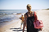 Frau läuft mit Kind am Strand