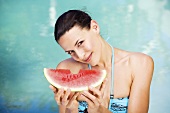 Frau mit Wassermelone am Swimmingpool