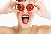 Junge Frau hält sich zwei Tomaten vor die Augen