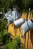 Watering cans on a fence