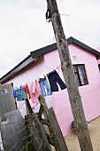 Washing hanging on a washing line in front of a pink house