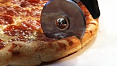 Pizza mit Pizzaschneider schneiden