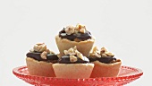 Small chocolate cream tarts with nuts on red stand