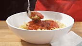 Putting cooked penne into a bowl