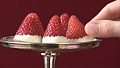 Hand taking a chocolate-dipped strawberry from a silver stand