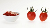 Ripe and unripe tomatoes and a small bowl of ketchup