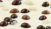 Geschmolzene weiße Schokolade mit Schokokugeln