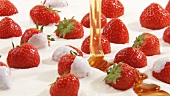 Pouring honey over strawberries and cream