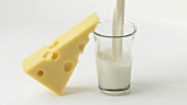 A piece of Emmental cheese & a glass of milk being poured