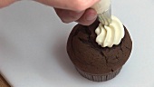 Schokoladen-Cupcake mit Sahne verzieren