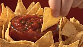 Dipping nachos in tomato salsa