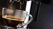 Espresso fliesst aus der Maschine in eine Glastasse