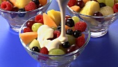 Pouring cream over fruit salad