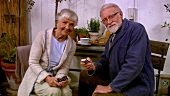 Elderly couple drinking coffee and using their mobile phone