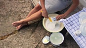 Frau beim Geschirr abwaschen vor einem Ferienhaus