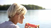 Junge Frau isst Wassermelone beim Picknick
