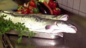 Koch trägt Platte mit Lachs in eine Restaurantküche
