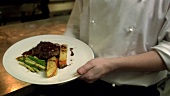 Chef presenting steak with vegetables