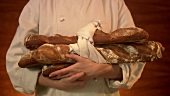 Baker with freshly baked baguettes