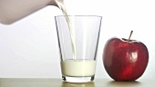 A glass of milk and a red apple