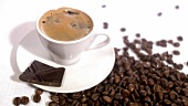 Eine Tasse Espresso mit Schokolade und Kaffeebohnen