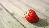 Eine Erdbeere auf Holzuntergrund