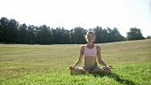 Woman in lotus position in a pasture
