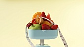 Fresh fruit and tape measure on kitchen scales