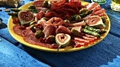 Plate of antipasti: salami, ham, figs, olives, asparagus