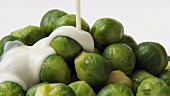 Pouring cheese sauce over cooked Brussels sprouts