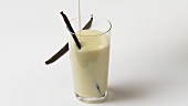 Pouring vanilla shake into a glass with a vanilla pod