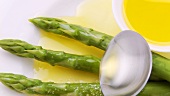 Sprinkling green asparagus with melted butter