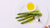 Sprinkling green asparagus with melted butter