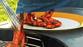Taking grilled chicken wings off a barbecue