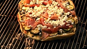 Pizza topped with courgettes, ham & goat's cheese on barbecue