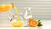 Orangensaft aus der Flasche in eine Kanne gießen
