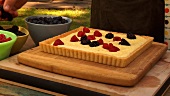 Putting fresh berries on cheese tart