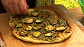 Putting grilled courgette slices on a pizza base