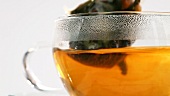Teebeutel in heisses Wasser tauchen, Tee mit Kandisstange umrühren