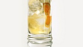 Limonade in ein Glas mit Eiswürfeln & Fruchtscheiben gießen