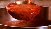 Tomatensauce mit einer Kelle aus dem Top schöpfen