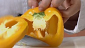 Eine gelbe Paprika halbieren und entkernen