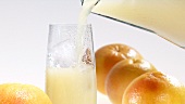 Pouring grapefruit juice into a glass of ice cubes
