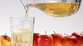 Pouring apple juice into a glass of ice cubes