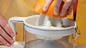 Squeezing an orange with an electric citrus squeezer