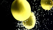 Zitronen fallen ins Wasser (Schwarzer Hintergrund)